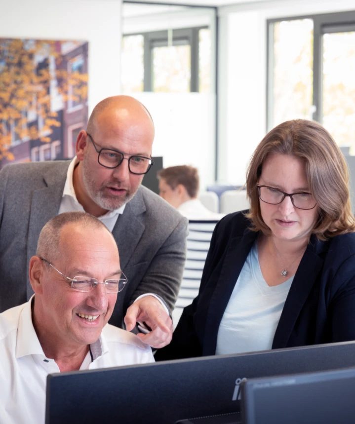 Drie collega's overleggen achter een beeldscherm